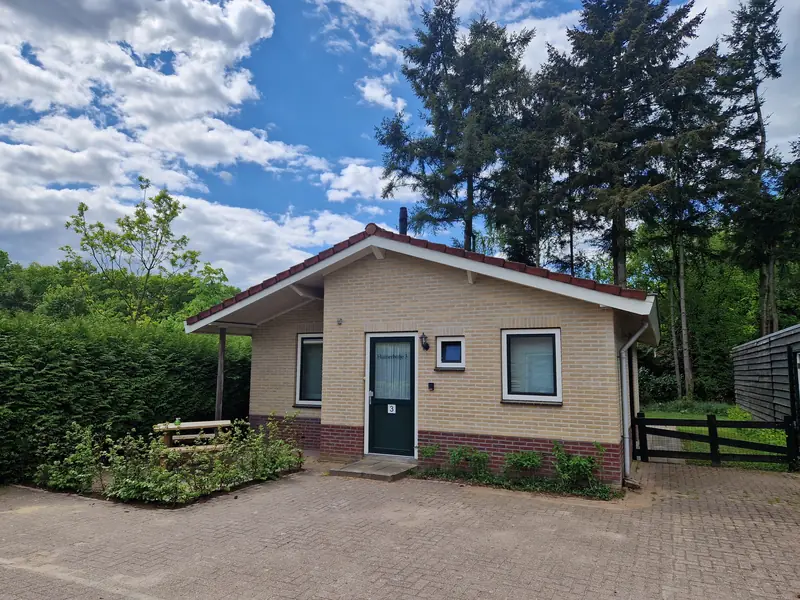 De voorkant van huisje 3 in de zomer, onder een blauwe lucht.